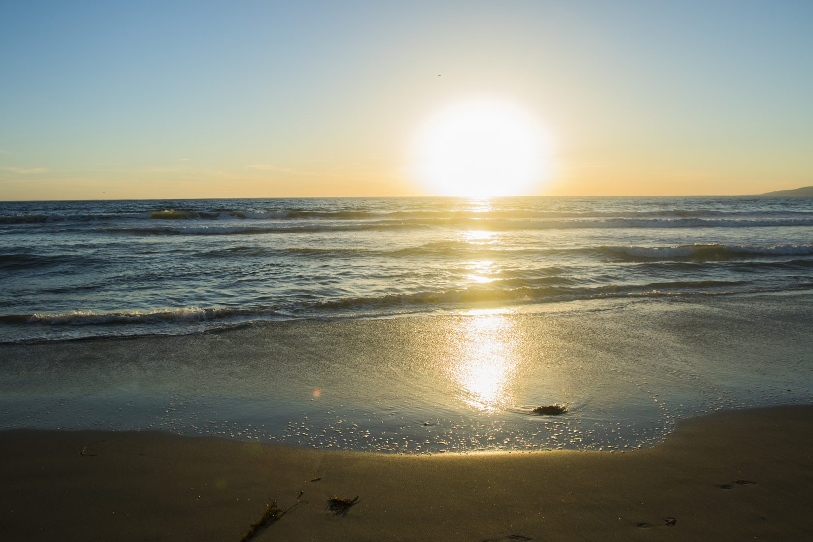 Sun reflecting on a calm beach at golden hour