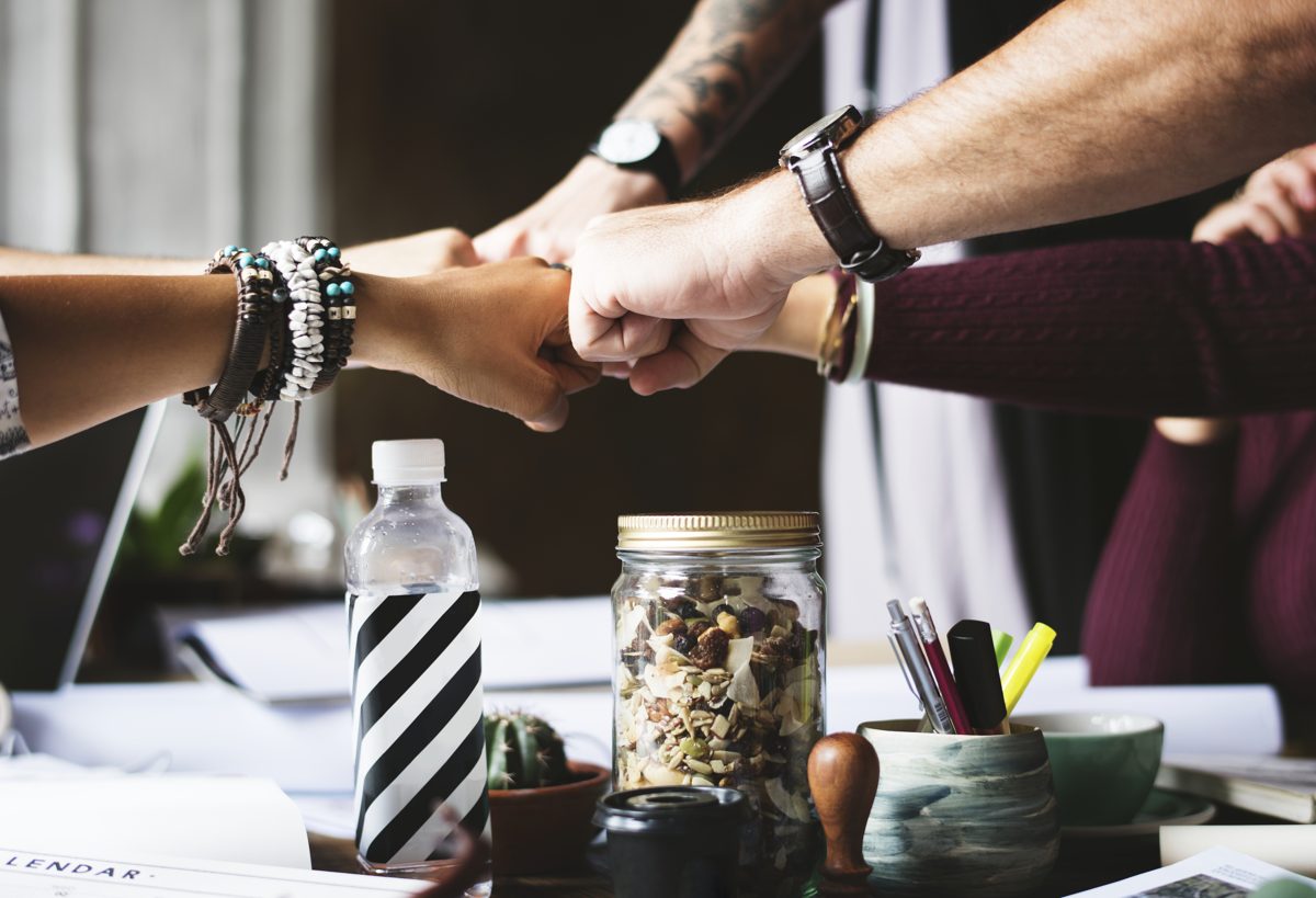 Colleagues fist-bumping over a desk