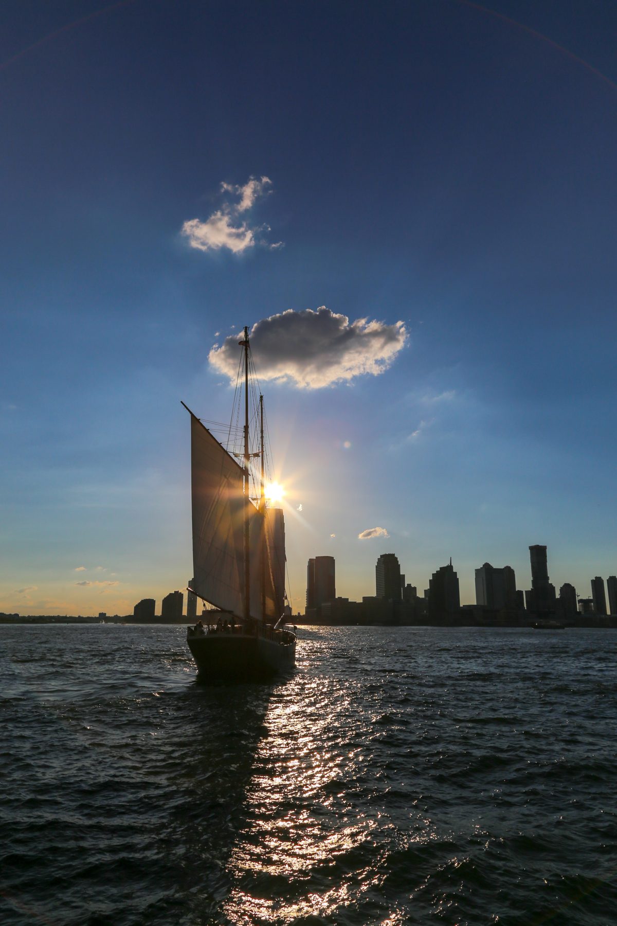 A sailboat gliding past a modern city skyline